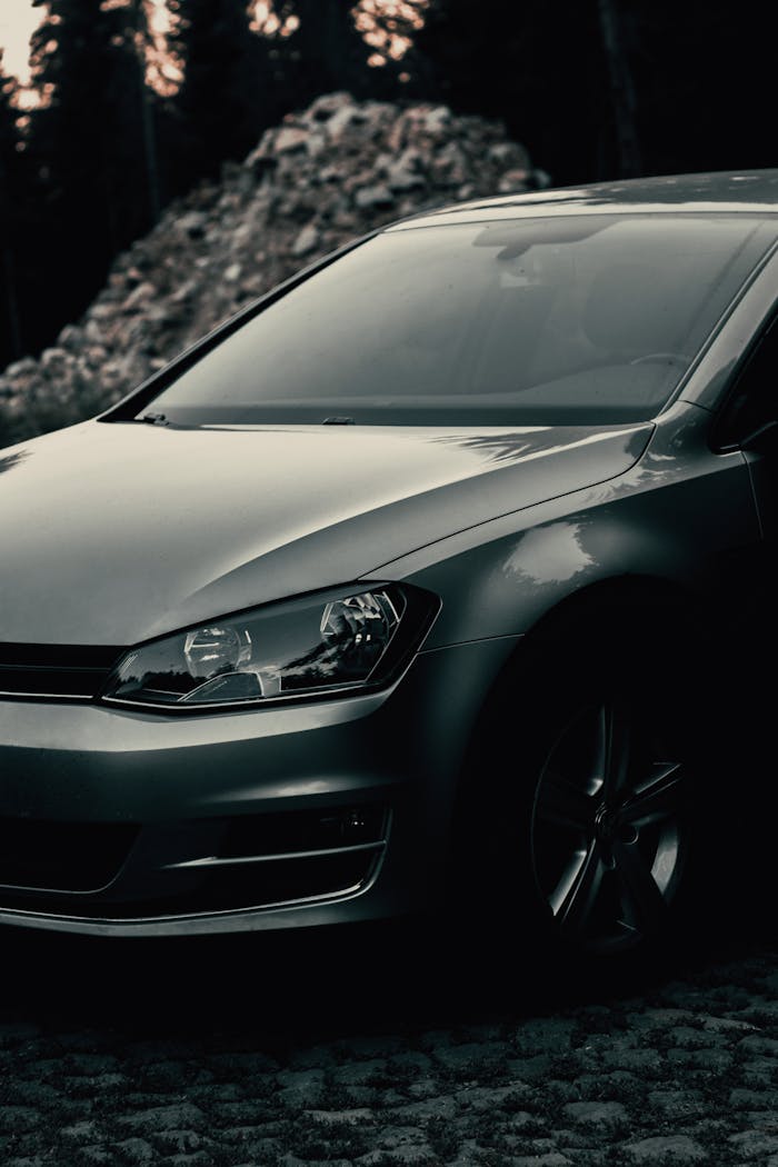 Close-up view of a sleek silver sedan parked outdoors with a dark, moody atmosphere.